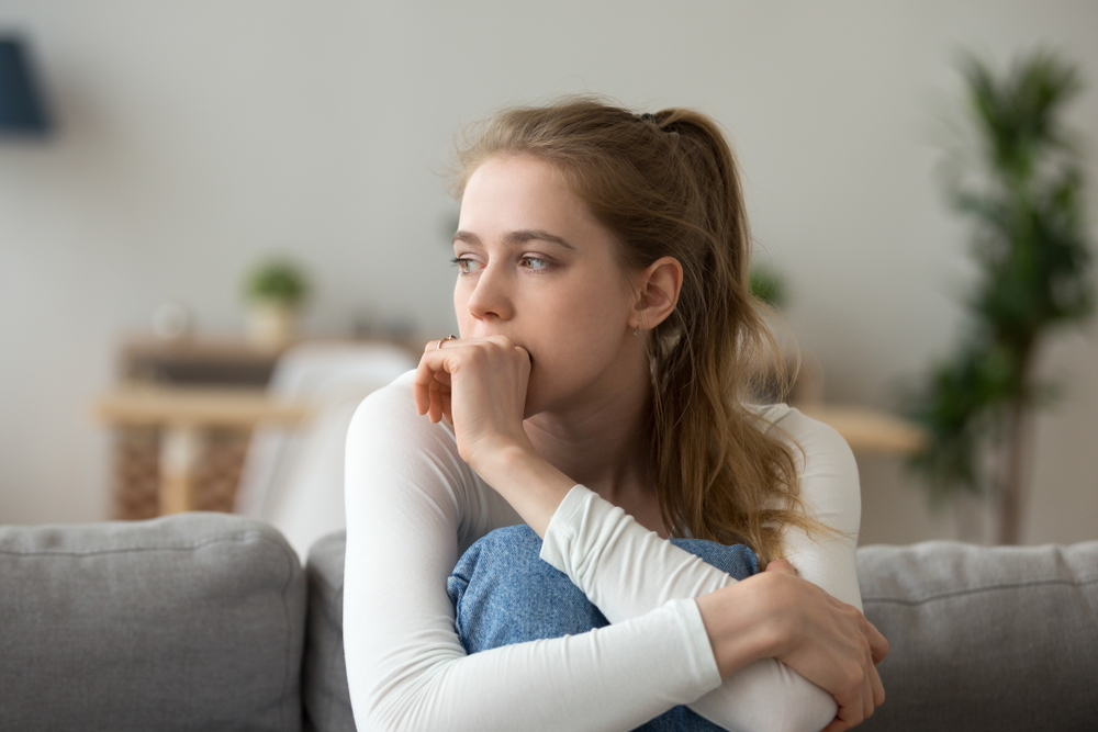 Stressed young woman sitting on couch